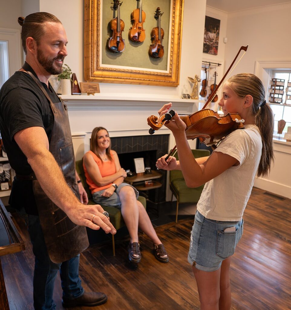 Girl shopping for a violin with her mom at a music store in St. George.